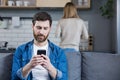 Close up photo. Conflict, young couple, family, man and woman. The man sits on the couch, looks at the phone, plays games, does Royalty Free Stock Photo