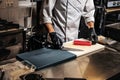 Close-up photo of a cook in uniform and gloves preparing sushi on cutting board in the kitchen. Royalty Free Stock Photo