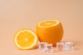 Close-up photo of cut orange and melting ice cubes isolated on sandy background Royalty Free Stock Photo