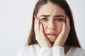 Close up photo of displeased frightened girl looking at camera touching face frowning over white background.