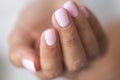 Close-up photo of elegant light pink manicure over white shirt background, tender women`s hands with perfect nails