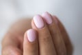 Close-up photo of elegant light pink manicure over white shirt background, tender women`s hands with perfect nails