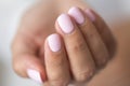 Close-up photo of elegant light pink manicure over white shirt background, tender women`s hands with perfect nails