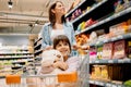 Close up photo of a family young woman and her cute little girl sitting inside the shopping cart embracing the toy while Royalty Free Stock Photo