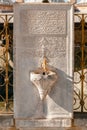 Close-up photo of a faucet on a big old marble stone with engraved old arabic writings in Mevlana Mausoleum in Konya