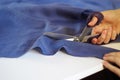 Close up photo of female hand with the scissors cutting the violet fabric