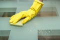 Close-up photo of female hand washing glass table in with cleaning spray and sponge wearing gloves in apartment Royalty Free Stock Photo