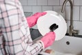 Close-up photo of female hands in pink rubber gloves washing dinner plate with dish brush Royalty Free Stock Photo