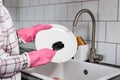 Close-up photo of female hands in pink rubber gloves washing dinner plate with dish brush Royalty Free Stock Photo