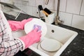 Close-up photo of female hands washing white dinner plate with sponge and foam in kitchen sink Royalty Free Stock Photo