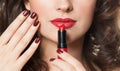 Close up photo of female lips and red lipstick in hand with dark red manicured nails. Beauty and cosmetic concept, close up beauty Royalty Free Stock Photo