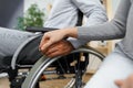 Close up of female touching hand of disabled man in wheelchair for support