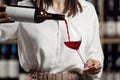 Female waiter pouring red wine into wineglass, close up. Sommelier pours alcoholic drink Royalty Free Stock Photo