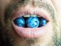 Close-up photo of a fragment of the bottom of an unshaven male face with open mouth and blueberries in it