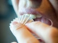 Close-up photo of a fragment of a woman`s face, open mouth, fingers bring candy in a wrapper