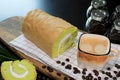 Close-up photo Fresh Hot Coffee in the brown and white color cup with coffee beans, and Pandanus Yam Roll Cake with white cream