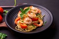 Close-up photo-fried spaghetti or fried noodles Pasta with tomato sauce and shrimp, basil, and tomatoes on a black plate On a Royalty Free Stock Photo
