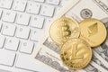Close up photo of golden coins of bitcoin ethereum and litecoin lying on paper american money and white keyboard