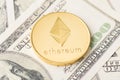 Close up photo of golden shiny glowing ethereum coin lying on american bill money