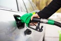 Close-up photo of hand holding fuel pump and refilling car at petrol station