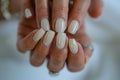 Close-up shot of professionally manicured hands featuring glossy neutral nail polish