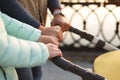 Close up of young loving family hands holding baby pram by the lake. Parents with stroller in autumn park on sunset. Love, parenth Royalty Free Stock Photo