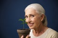 Close-up photo of happy aged woman showing young plant in the sp Royalty Free Stock Photo