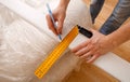 Close up photo of hardworking holding ruler and pencil while making marks on wood at table Royalty Free Stock Photo