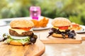 Delicious homemade hamburgers on a wooden cutting board, ready to be eaten by the whole family on a wooden table at home. Royalty Free Stock Photo