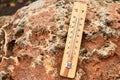 Close-up photo of household alcohol thermometer on a stone showing temperature in degrees Celsius. Outdoors. Close-up, selective