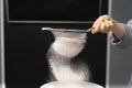 Close up photo of a human hand sieving flour and getting ready for baking.