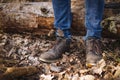 Close up photo of human legs in old leather boots and blue jeans standing on the ground with dried leaves Royalty Free Stock Photo