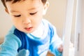 Close-up photo of an ill male infant or baby with snot under the nose on his face wearing blue pajamas. Multicultural.