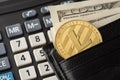 Close up photo image of golden litecoin laying in black pocket wallet together with american paper banknotes with calculator on Royalty Free Stock Photo