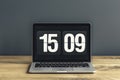 Close-up photo of laptop with time screensaver placed on wooden Royalty Free Stock Photo