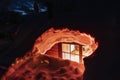 Close up photo of light window of mountain cabin fully buried under snow, view to inside room in house. Northern Sweden, Lapland,