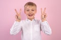 Close up photo little age beautiful boy hold arm show victory sign say hi to friends relatives positive optimistic wear white Royalty Free Stock Photo