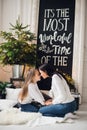 Close-up photo of little girl in knitted sweater kiss her mother while sitting on sofa at Christmas Royalty Free Stock Photo