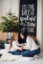 Close-up photo of little girl in knitted sweater kiss her mother while sitting on sofa at Christmas Royalty Free Stock Photo