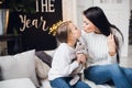 Close-up photo of little girl in knitted sweater kiss her mother while sitting on sofa at Christmas Royalty Free Stock Photo