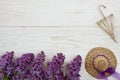 Close up photo with Little straw hat, decorative umbrella and lilac branches on a white wooden background. Spring background