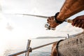 Close up of male hands holding fishing rod while fishing on sailboat in open sea Royalty Free Stock Photo