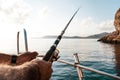 Close up of male hands holding fishing rod while fishing on sailboat in open sea Royalty Free Stock Photo