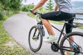 Close-up photo of a man dressed in cycling clothes starting riding a modern bicycle on the asphalt out-of-town bicycle path. Royalty Free Stock Photo