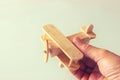 Close up photo of man's hand holding wooden toy airplane over wooden background. filtered image. aspiration and simplicity concept Royalty Free Stock Photo