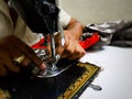 Close up photo of manual sewing machine with tailor hands stitching red cloth with selective focus