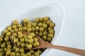 Close up photo of marinated green olive in white bowl with wooden spoon Royalty Free Stock Photo