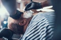 Hairstylist shaving customer beard by sharp razor