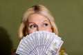 Close up photo of mature age wealthy woman hiding face anonymous poker player holding much money isolated on khaki color Royalty Free Stock Photo