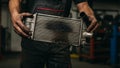 Old leaky car radiator. Close-up of mechanic holding damaged car radiator, ideal for automotive repair or maintenance blogs